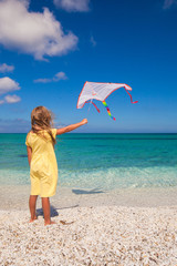 Little cute girl playing with flying kite on tropical beach