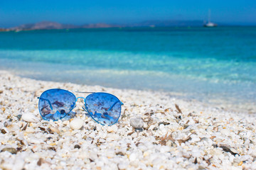 Fototapeta na wymiar Close up of colorful blue sunglasses on tropical beach
