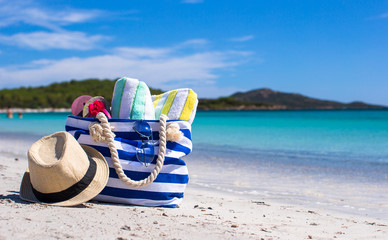 Blue bag, straw hat, flip flops and towel on white tropical