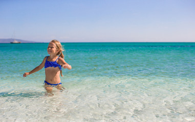 Adorable little girl have fun at tropical beach in shallow water