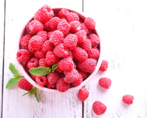 Ripe sweet raspberries in bowl on table close-up