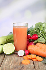 Fresh carrot juice with vegetables on wooden table