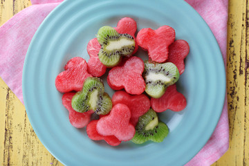 Slices of watermelon in plate on napkin on wooden background
