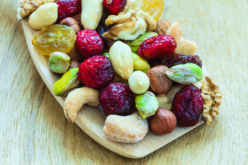 Varieties of dried fruits and nuts on wooden spoon.