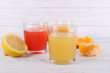 Different sliced citrus fruits and glasses of juice