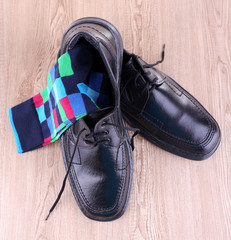 Black man's shoes and pair of socks on wooden background