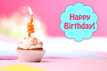 Delicious birthday cupcake on table on bright background