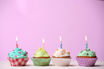 Delicious birthday cupcakes on table on pink background