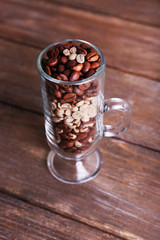 Glass of coffee beans on wooden background