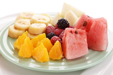 Slices of fruits with berries on plate close up