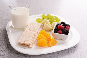 Slices of fruits with crispbreads and glass of milk