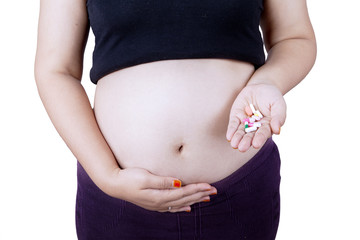 Pregnant tummy with pills on hand