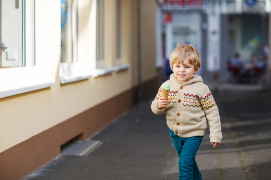 Happy little boy eating ice cream, outdoors
