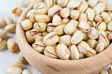 full bowl of pistachio on wooden surface
