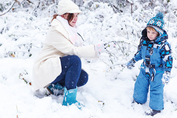 Fototapeta na wymiar Little preschool boy and his mother playing with first snow in p