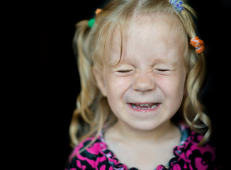 Cute little girl smiling over dark background.