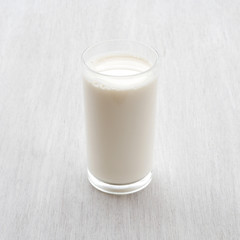Glass of milk on white wooden floor