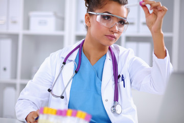 Woman researcher is surrounded by medical vials and flasks,