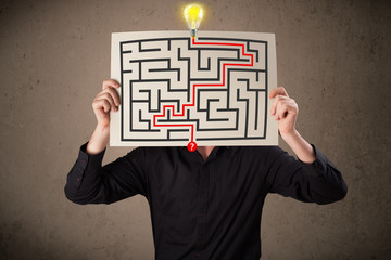 Businessman holding a paper with a labyrinth on it in front of h
