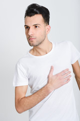 Serious young man standing against white background