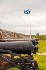 scottish flag next to cannons at fort george