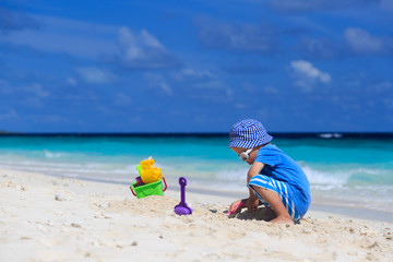Fototapeta na wymiar little boy playing with sand on the beach