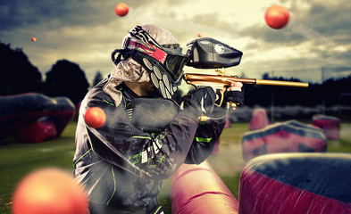 Paintball player in mid game being shot at - obrazy, fototapety, plakaty