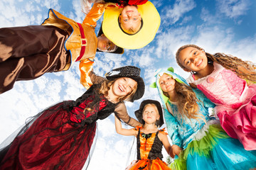 Many kids look down in circle wearing costumes