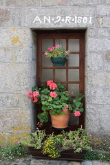 Ancienne maisone en pierre à Pont-Croix, Brategne, France.  Pot de fleurs de geranium devant la port.