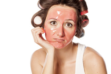 portrait of a bored young woman with curlers and face mask