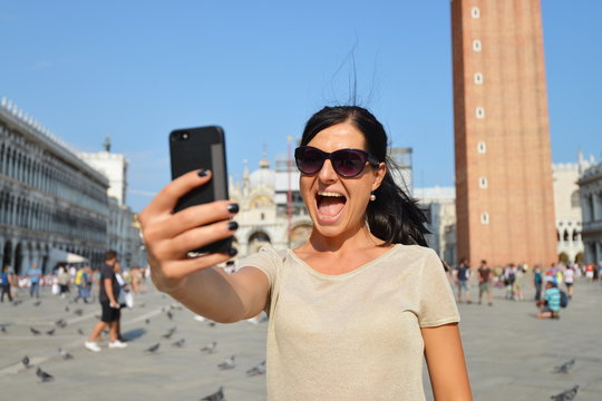 A beautiful young woman taking herself a selfie in Venice