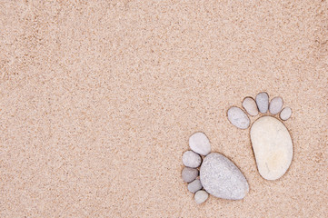Fototapeta na wymiar pair feet made of a stone on the sea sand