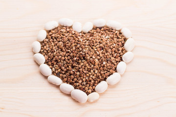Heart-shaped buckwheat with beans on wooden background