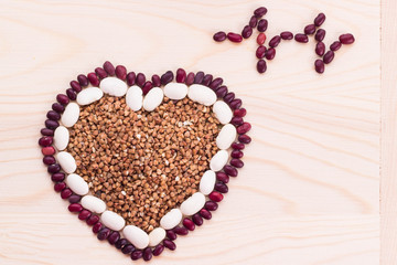 Heart-shaped buckwheat with beans on wooden background