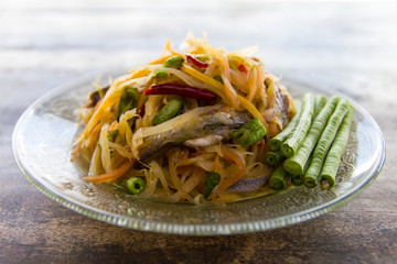 Papaya salad with fermented fish and lentils on a glass dish
