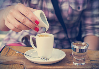 Woman pouring cream into coffee