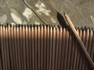Row of identical pencils  on a old wooden background