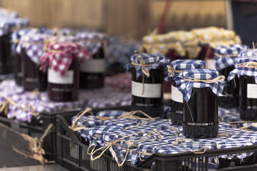 Many preserving jars with dark jam in a market