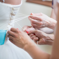 Obraz na płótnie Canvas Bridesmaids helping the bride to put her dress on