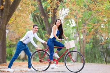 Plakat Teen couple with bike in the park in autumn time