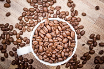 White coffee mug filled with coffee seeds.