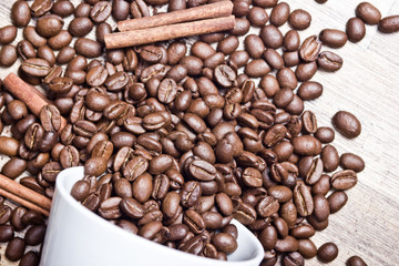Fallen white coffee mug with coffee beans all around.
