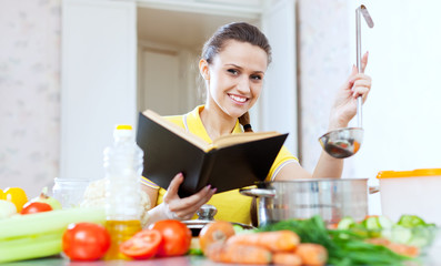 happy woman cooking with book a