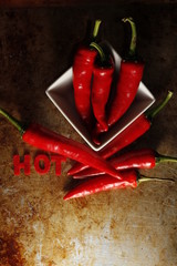 hot chili peppers with word hot in bowl on old vintage desk