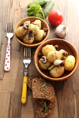 Young boiled potatoes in bowl on wooden table, close up