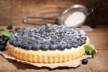 Tasty homemade pie with blueberries on wooden table