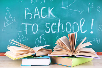 School supplies on table on blackboard background
