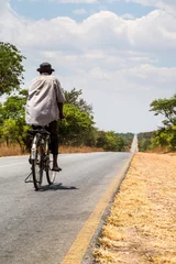Fototapeten Local man riding on a bike on a desolated road © pwollinga