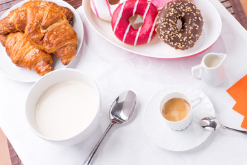 Prima colazione con donuts, brioches, latte e caffè