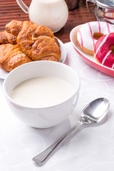 Prima colazione con donuts, brioches e tazza di  latte